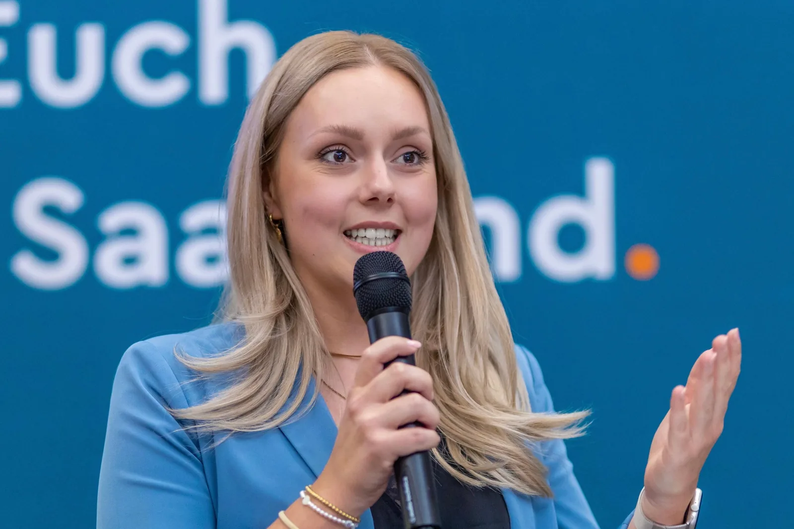 Carolin Mathieu (CDU) spricht mit Mikrofon vor dem Banner „Da. Für Euch. Fürs Saarland.“